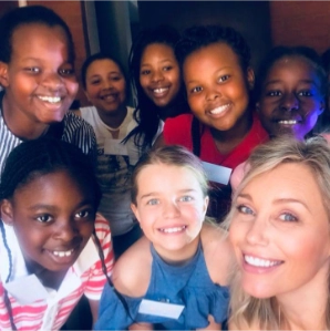 Anri van der Linde with young students taking a selfie.